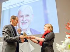 Elke Schaper vom AVETH übergibt Urs Gonzenbach, Oberassistent von Preisträger Luwig Gauckler, das Goldene Dreirad. (Bild: Tom Kawara)